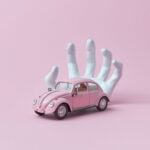 photo of a white hand behind a pink car toy