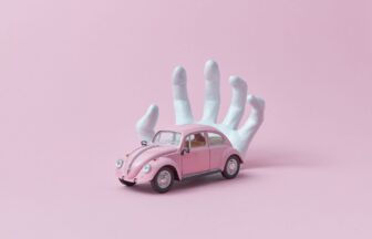 photo of a white hand behind a pink car toy