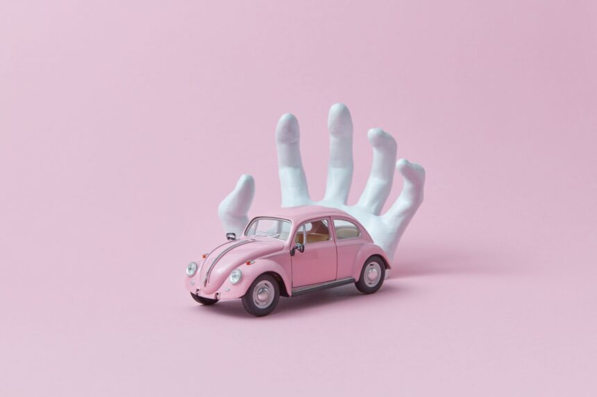 photo of a white hand behind a pink car toy