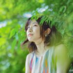 a woman in printed tank top beside green trees