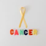 yellow ribbon over word cancer made of colorful letters