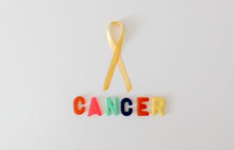 yellow ribbon over word cancer made of colorful letters